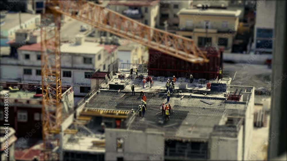 Construction workers wearing high visual clothing and laying steel reinforcement preparing for the concrete to be poured. Tilt and shift, stop motion, miniature world. Construction workers wearing high visual clothing and laying steel reinforcement preparing for the concrete to be poured. Tilt and shift, stop motion, miniature world.