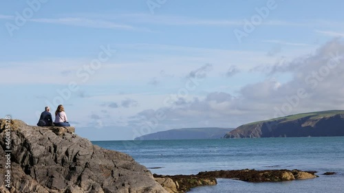 Tourists enjoying the view on Cwm-yr-Eglwys beach. Cwm-yr-Eglwys, Dinas, Pembrokeshire, Wales, UK.  photo