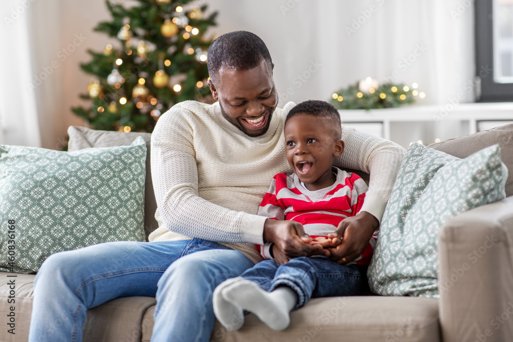 family, winter holidays and people concept - happy smiling african american father playing with baby son at home on christmas family, winter holidays and people concept - happy smiling african american father playing with baby son at home on christmas