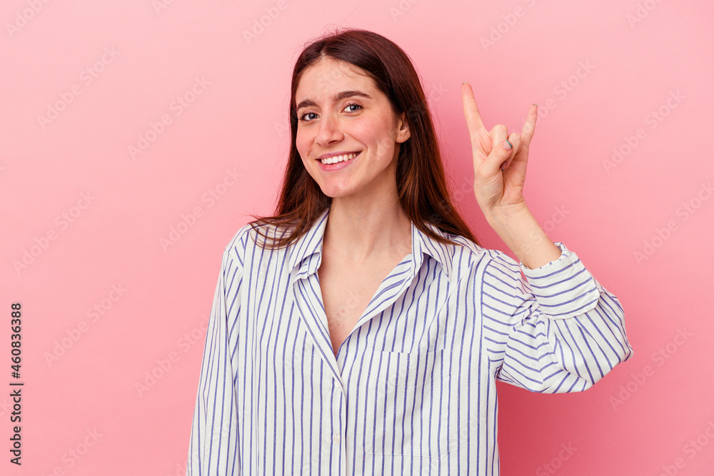 Young caucasian woman isolated on pink background showing a horns gesture as a revolution concept. Young caucasian woman isolated on pink background showing a horns gesture as a revolution concept.