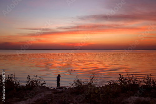 5 year old boy walks along the coast at sunset in autumn, escape to nature, digital detox, time to be alone. Beautiful silhouette in lights of the sunset. Autumn outside lifestyle