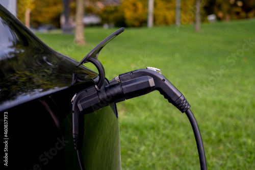 Close up of a plug connected to electric hybrid car charger. Green transportation, no emission, new technology concept.