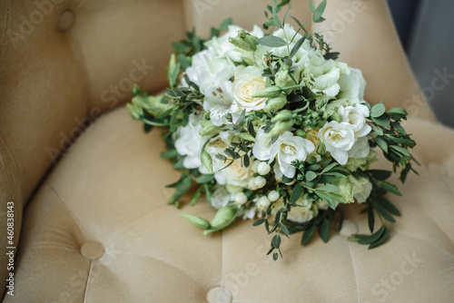 a delicate white wedding bouquet of flowers lies on a velvet armchair, a touching light photo