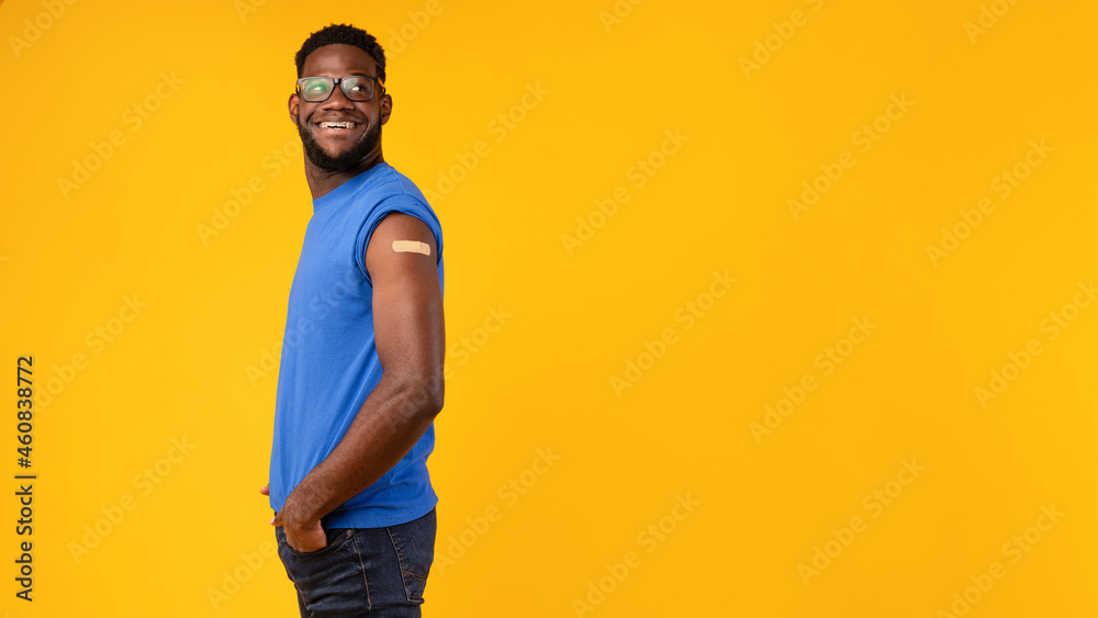 Black Male Showing Vaccinated Arm After Shot On Yellow Background Black Male Showing Vaccinated Arm After Shot On Yellow Background