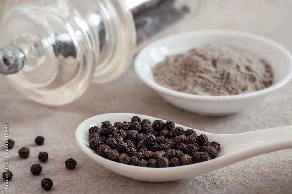 Black pepper corn on spoon and black pepper powder in bowl. Black pepper corn on spoon and black pepper powder in bowl.