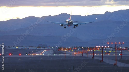 Generic Passenger Jet Airliner Landing Arriving at Airport at Night with Runway Lights Surrounded by Mountains at Sunset near Las Vegas Nevada