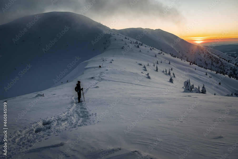 torist silhouette watching on sunset in winter mountains