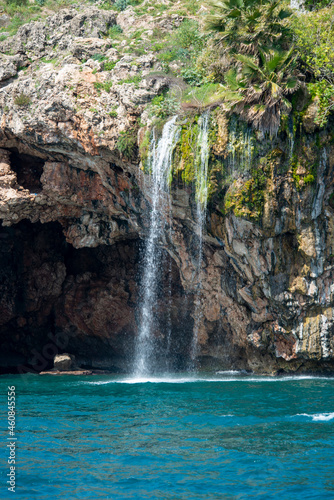 Freshwater waterfall falling on the shores of the Mediterranean between caves and cliffs