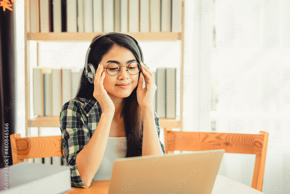 Young female student in plaid shirt sitting at the table using laptop when studying. Young female student in plaid shirt sitting at the table using laptop when studying.