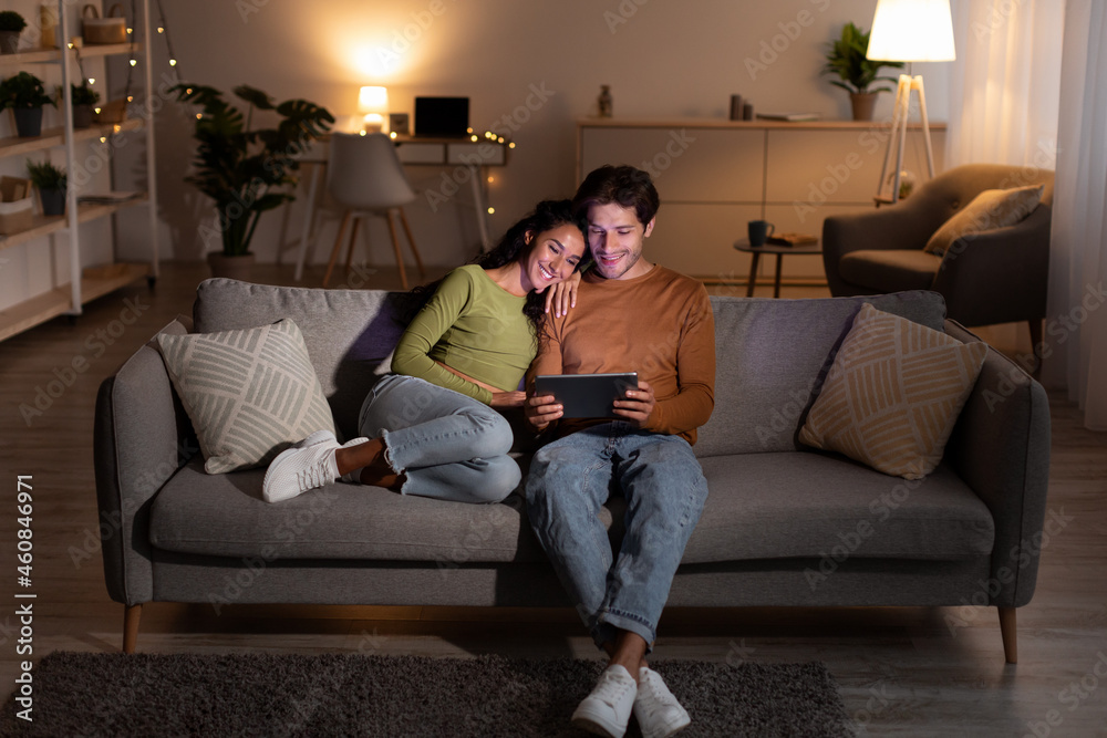 Couple Browsing Internet On Tablet Sitting On Sofa At Home Couple Browsing Internet On Tablet Sitting On Sofa At Home