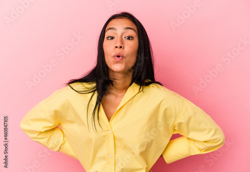 Young Venezuelan woman isolated on pink background being shocked because of something she has seen. © Asier