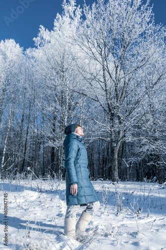 Young woman is resting in the winter forest. Blue coat on a background of white snow