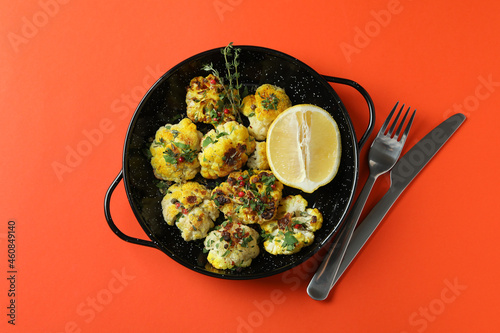 Concept of tasty food with baked cauliflower on orange background