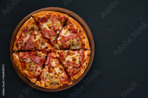Top view of pizza isolated on black, left frame with copy space