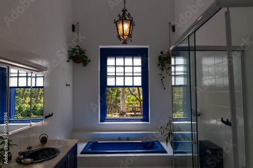 beautiful bathroom of an old farm in São Paulo, Campinas. Bathtub and blue windows. With a view of nature. And antique chandelier