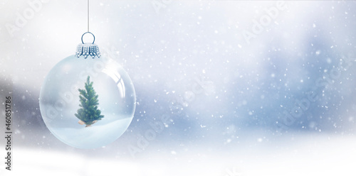 Gläserne Weihnachtskugel vor unscharfem Blauem Hintergrund mit Schneeflocken