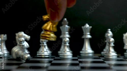 Gold horse chess piece knock and win over silver team on black background (Concept for company strategy, business victory or decision) photo