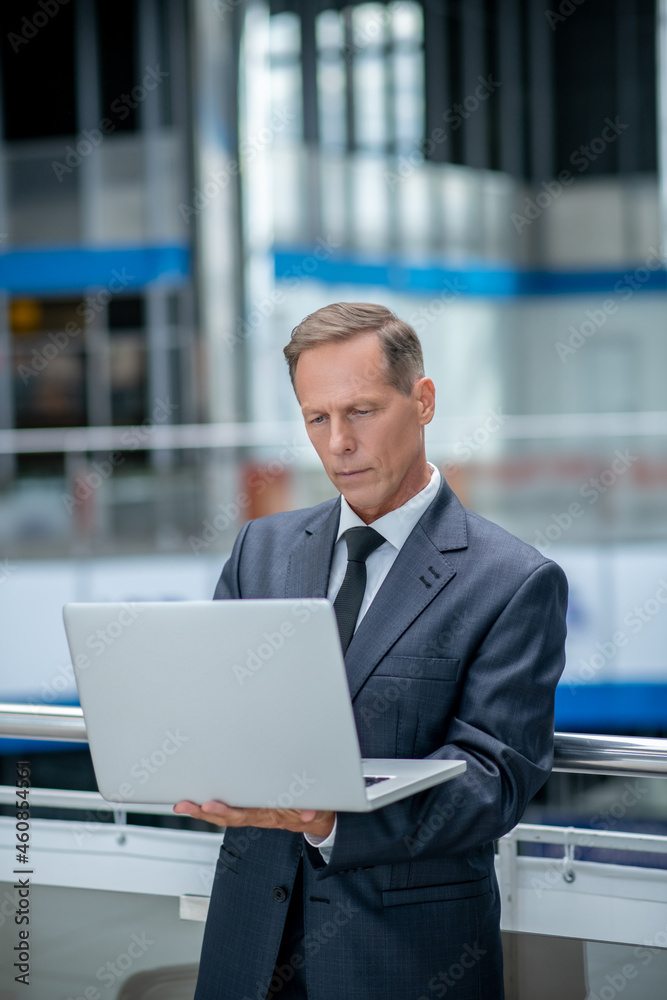 Serious man looking at laptop at airport Serious man looking at laptop at airport
