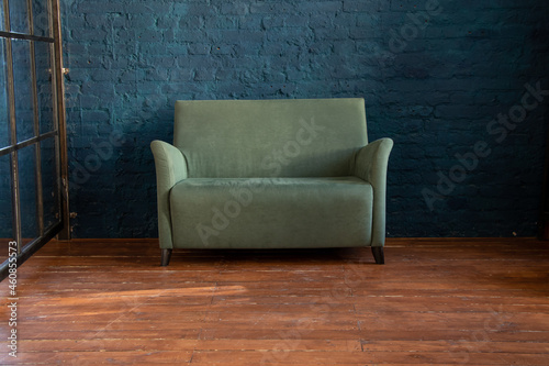 green soft sofa near the blue wall on the wooden floor in the room, upholstered furniture in the apartment, sofa in the hall photo