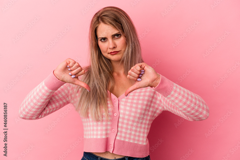 Young russian woman isolated on pink background showing thumb down and expressing dislike.