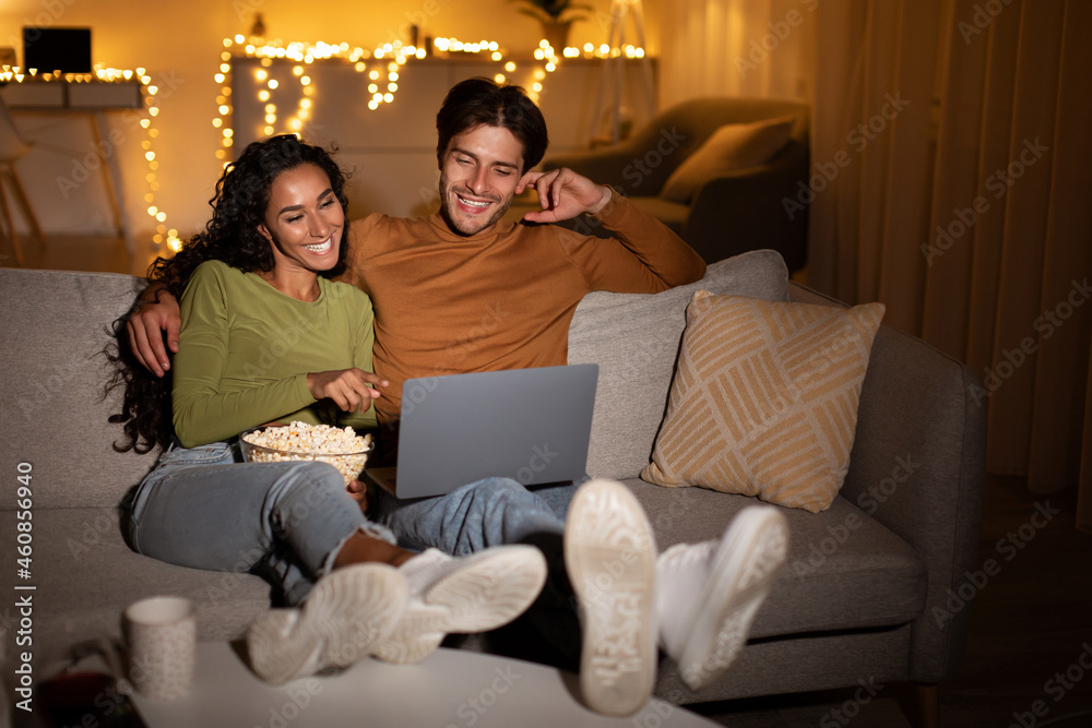 Cheerful Couple Enjoying Movie Sitting At Laptop Computer At Home Cheerful Couple Enjoying Movie Sitting At Laptop Computer At Home