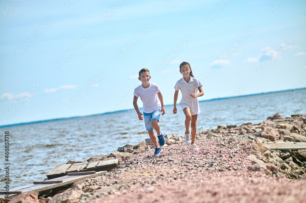 Fototapeta premium Two kinds running on a beach and feeling great