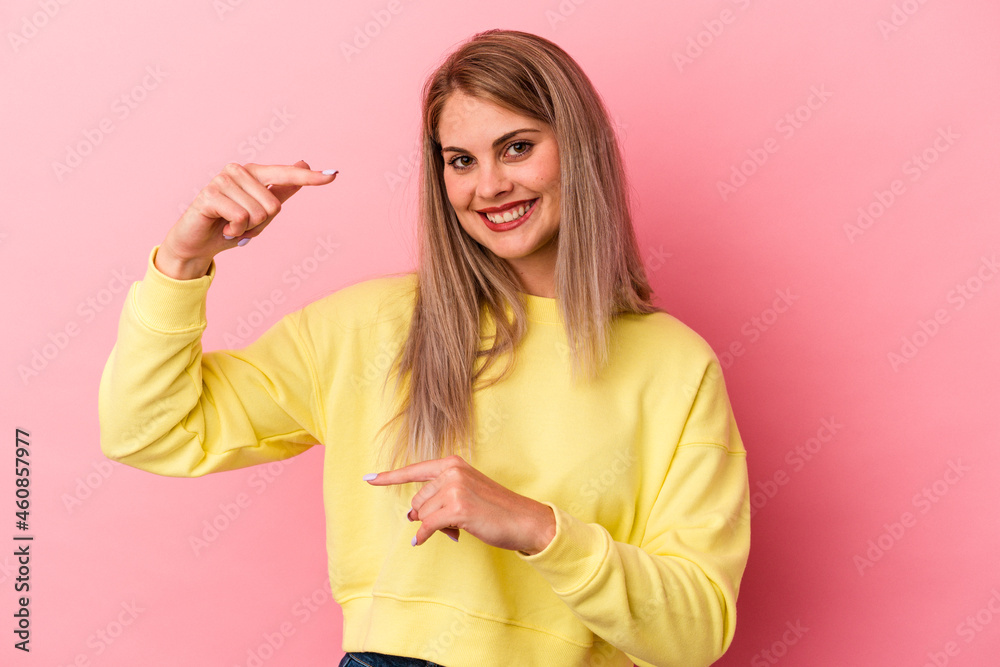 Young russian woman isolated on pink background holding something little with forefingers, smiling and confident. Young russian woman isolated on pink background holding something little with forefingers, smiling and confident.