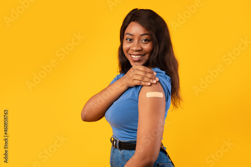 Cheerful Vaccinated African Woman Showing Arm After Vaccine Injection, Studio