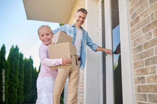 Little girl with box and dad entering house