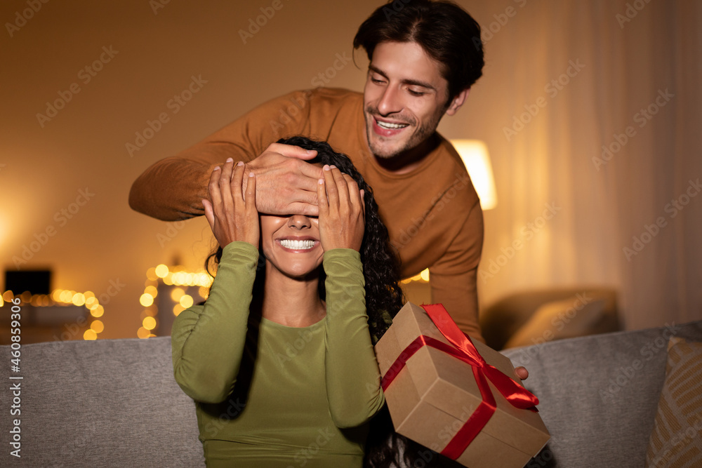 Obraz premium Boyfriend Surprising Girlfriend With Gift Closing Her Eyes At Home