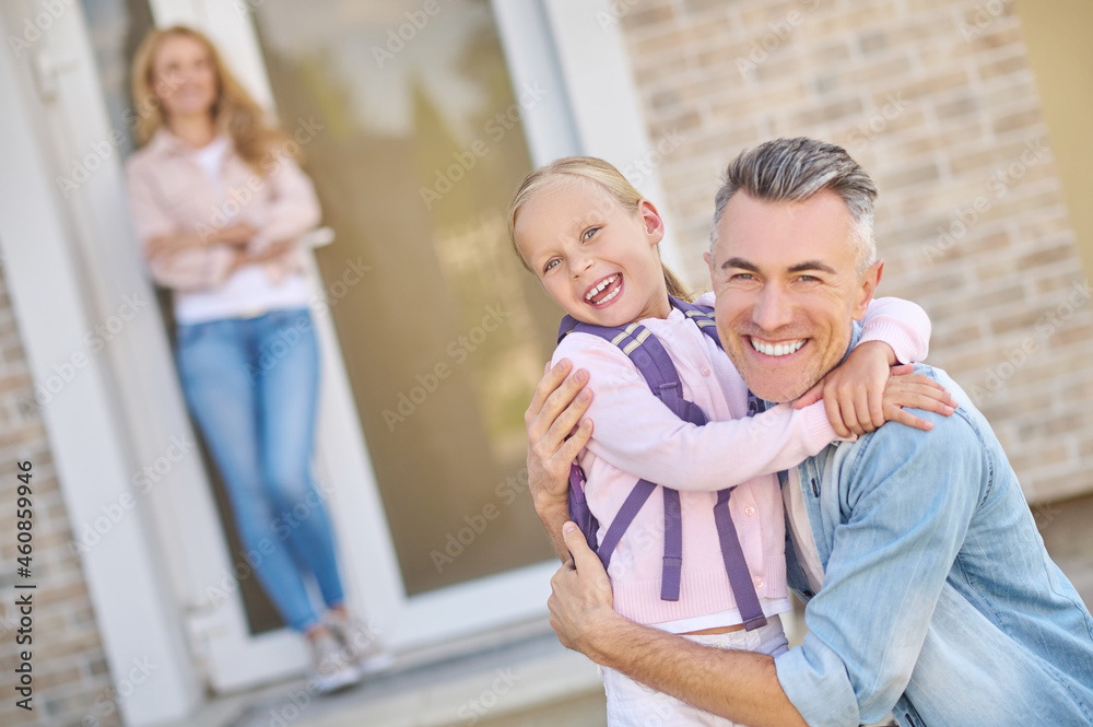 Obraz premium Joyful dad and daughter hugging near house