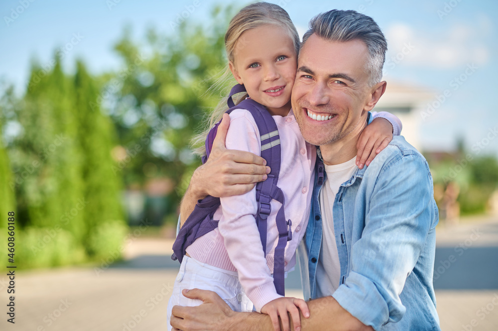 Obraz premium Cheerful dad and daughter hugging on walk