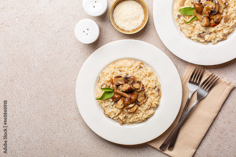 Risotto with mix of mushroom and taleggio cheese on stone beige table. Two portions. Top view. Copy space. Risotto with mix of mushroom and taleggio cheese on stone beige table. Two portions. Top view. Copy space.