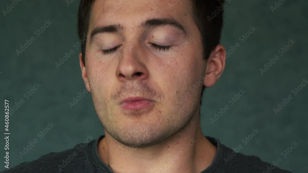 man sneezes close-up while standing in front of the camera in a dark room man sneezes close-up while standing in front of the camera in a dark room