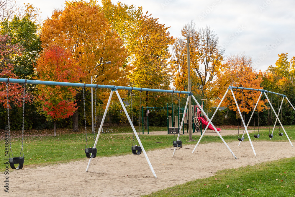 Public park with playground in autumn with swings and beautiful trees in background. Fall season.