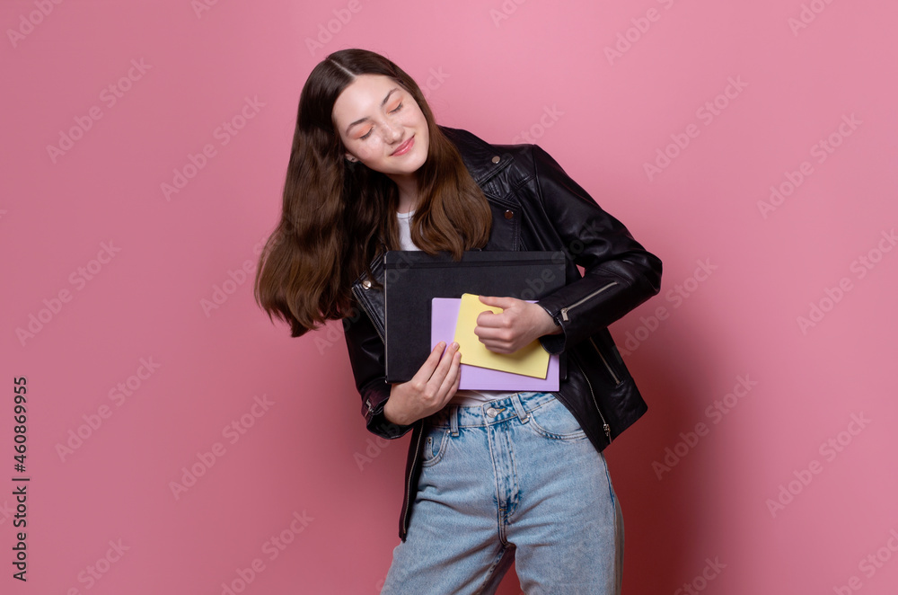 cheerful teenage school girl playing imagine guitar happy with a good grade wears a black leather jacket, listens to rock music, rock and roll mood isolated on pink background cheerful teenage school girl playing imagine guitar happy with a good grade wears a black leather jacket, listens to rock music, rock and roll mood isolated on pink background