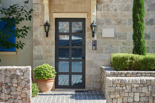 фотографія Modern house facade with stone finished wall, glass door and bushes in europe
