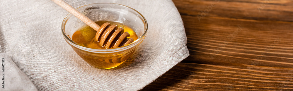 bowl with honey and dipper on linen napkin and wooden table, banner bowl with honey and dipper on linen napkin and wooden table, banner