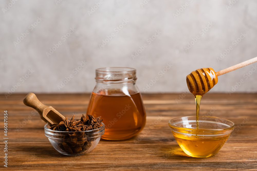 wooden dipper and scoop near jar and bowls with honey and anise seeds on grey marble background wooden dipper and scoop near jar and bowls with honey and anise seeds on grey marble background