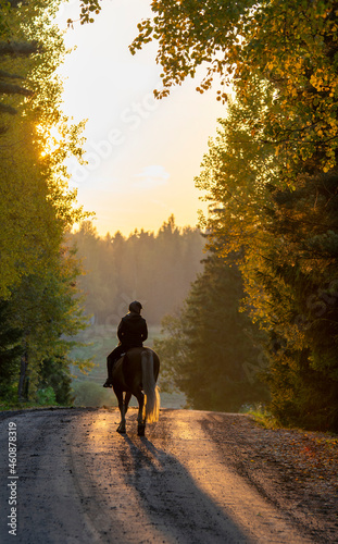 Woman horseback riding on the country road at sunset © citikka