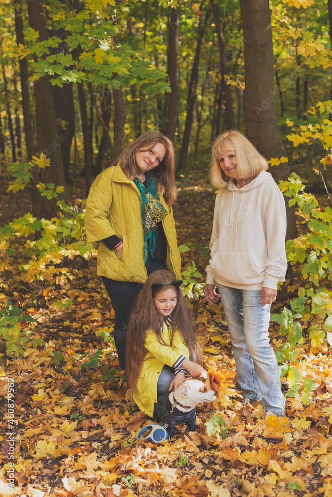 Portrait of three generations of happy beautiful women and dog looking at camera, hugging and smiling in autumn nature. Portrait of three generations of happy beautiful women and dog looking at camera, hugging and smiling in autumn nature.