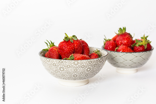 Strawberries in round plates, arranged on a white background.