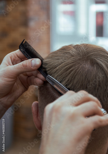 Hairdrasser making a haircut with scissors