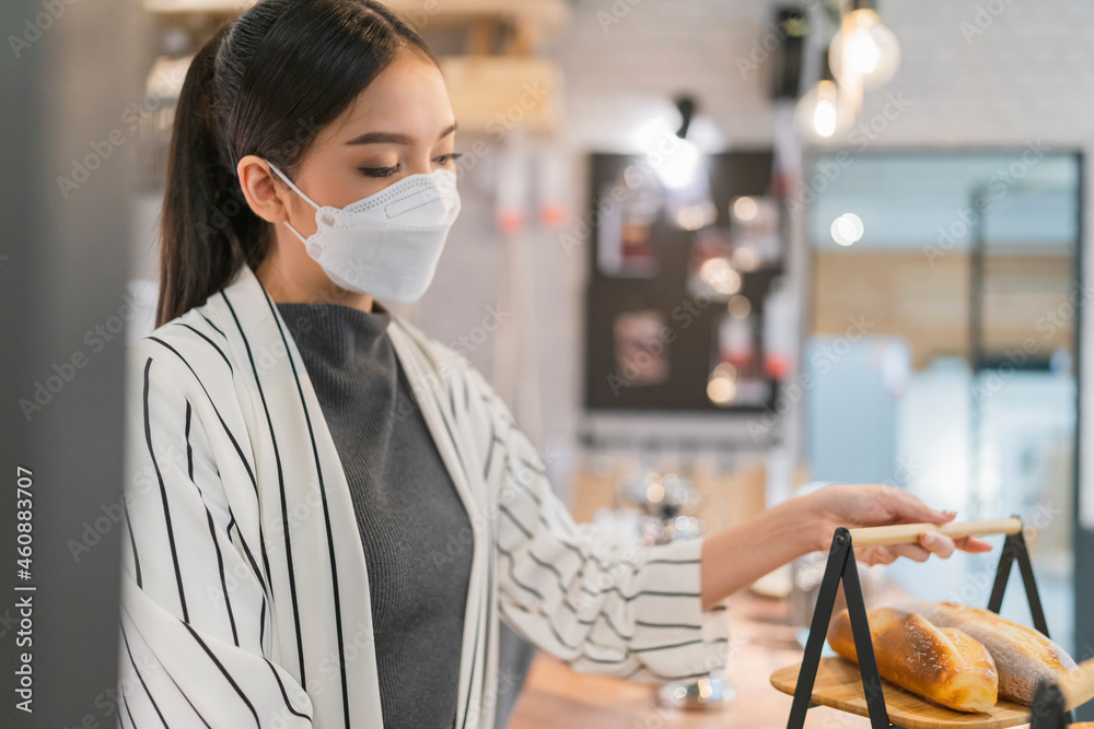 asian female coffee shop owner preapre arrange bakery bread basket before shop is open small business concept,asian business owner weaing face mask at coffeeshop background
