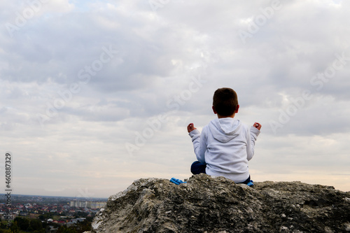 child meditates in nature on a background of clouds photo