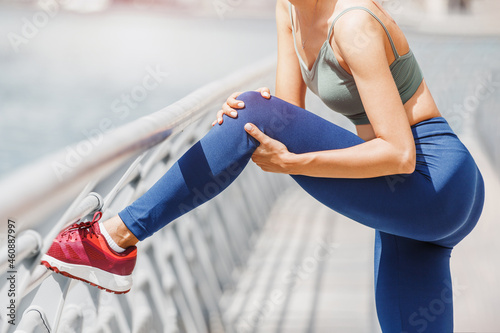 Young woman was running along the embankment and suddenly felt a sharp pain in the knee joint due to a dislocation or rupture of the meniscus photo