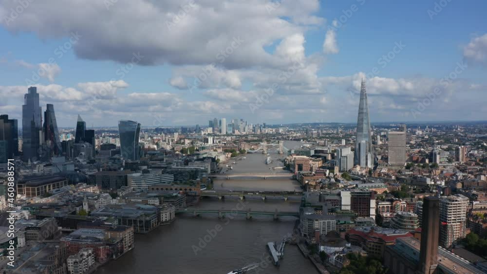 Backwards fly above River Thames, revealing modern skyscrapers in City district, Millennium footbridge and Tate Modern art gallery. Aerial view of city centre. London, UK Backwards fly above River Thames, revealing modern skyscrapers in City district, Millennium footbridge and Tate Modern art gallery. Aerial view of city centre. London, UK
