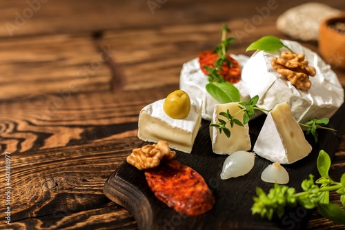 Camembert cheese on a rustic background. Noble cheese with mold. An overhead view of cheese with noble white mold and walnuts on a cutting board