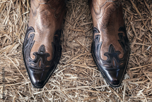 Cowboy boots standing on hay in barn