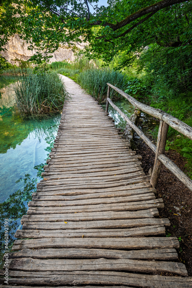 Plitvice, Croatia - Wooden walkway in Plitvice Lakes National Park on a bright summer day with crystal clear turquoise water, small waterfalls and green summer foliage